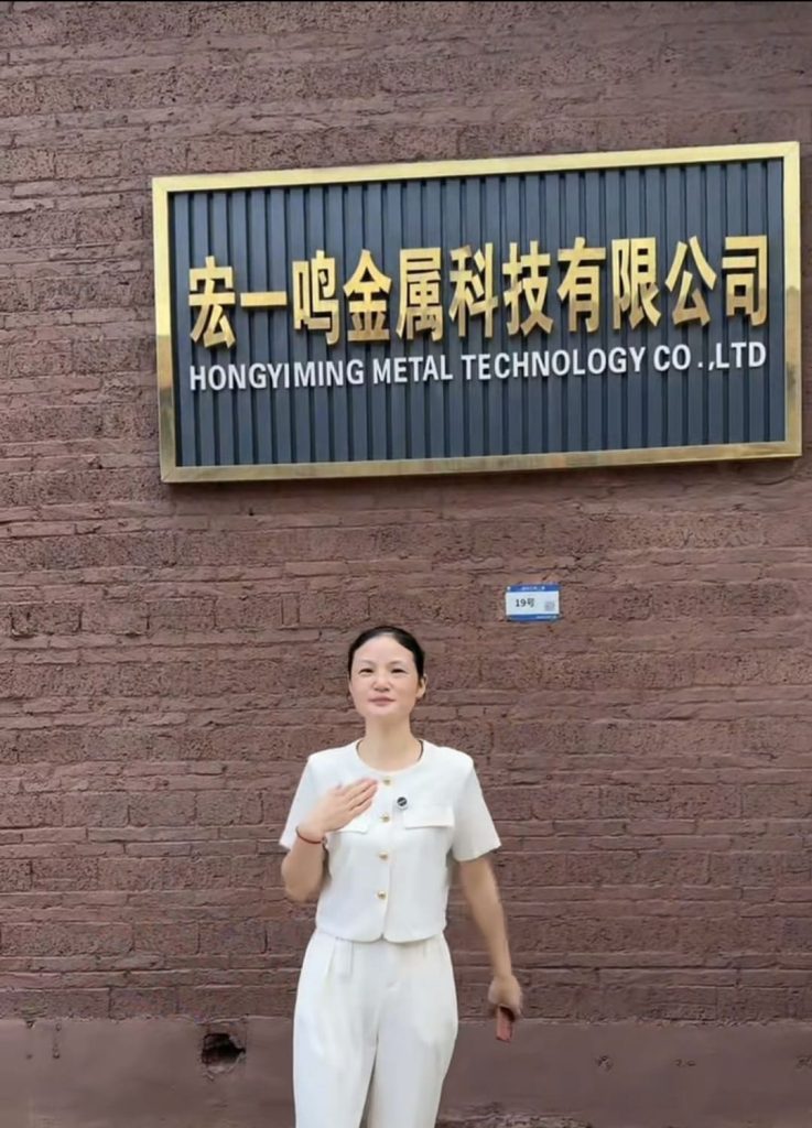 Hongyiming Metal Technology Co., Ltd company signage with team member at factory entrance